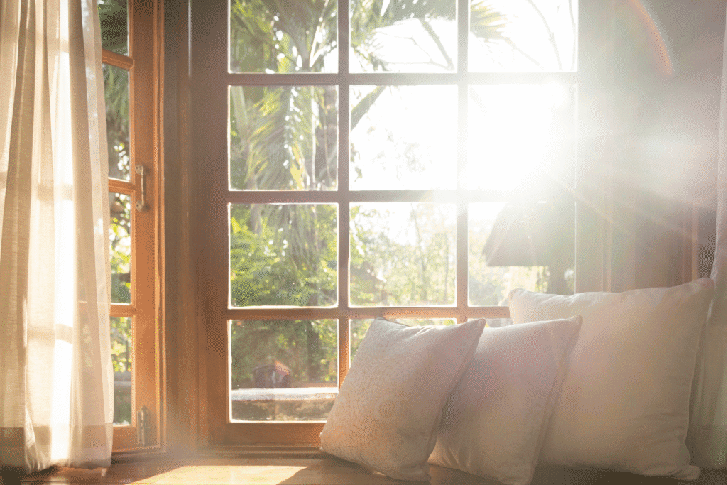 Soft morning light shining through a window onto a cushioned bench, symbolizing clarity, peace, and emotional healing.