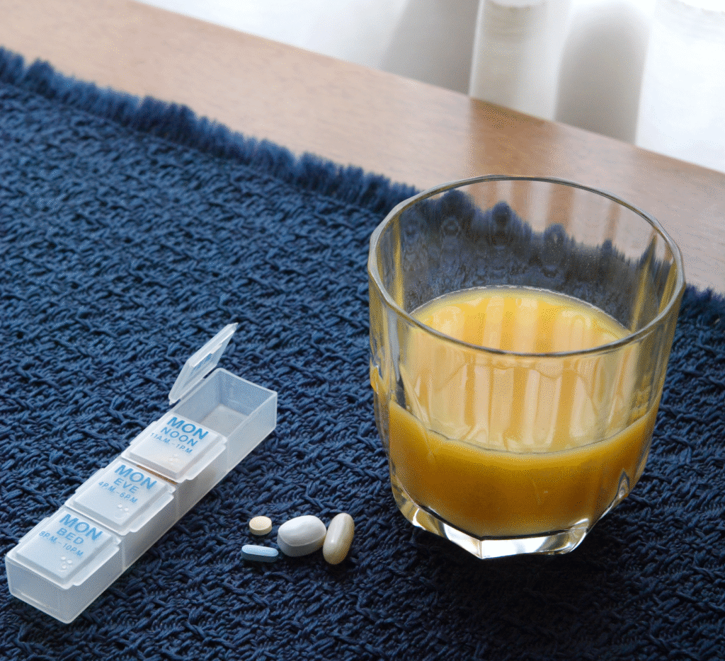 Daily pill organizer and glass of orange juice on a breakfast table, representing psychiatric medication support in a calm, comforting setting.